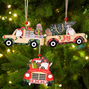 Close-up of wooden Christmas truck ornaments with gnome and tree hanging on a pine branch