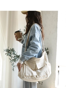 Detail of a cream canvas messenger bag with large flap pockets and spacious interior