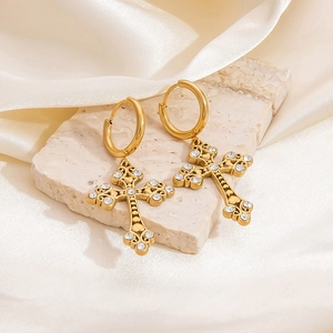 Detailed shot of gold cross hoop earrings with zircon crystals on silk and stone base