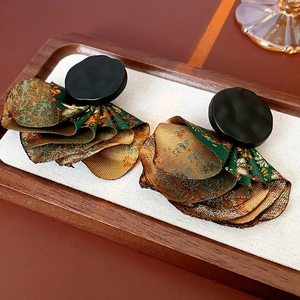 Detailed view of irregular petal earrings with black round studs and green gold fabric