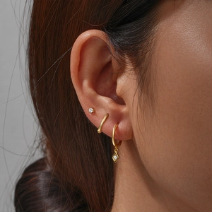 Detail of three gold earrings including diamond stud and polished hoop on ear
