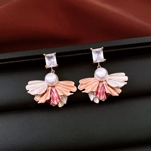 Détail de boucles d'oreilles vintage avec zircon, perle blanche et dégradé d'émail rose