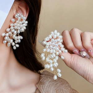 Détail de boucles d'oreilles pendantes à perles avec fleurs vintage et fils dorés