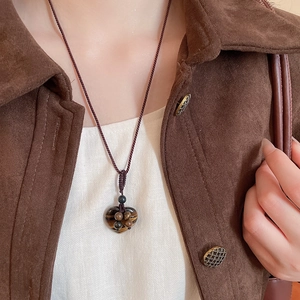 Macro shot of a vintage tiger eye heart pendant on a woven rope cord necklace