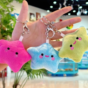 Detailed view of colorful star plush keychains in pink, blue, and green on a hand