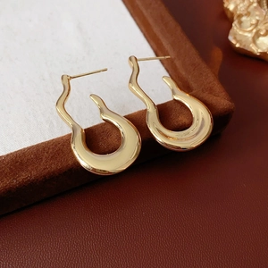 Macro shot of gold irregular wave-shaped gourd earrings on a brown velvet box