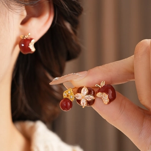Detailed macro view of dark red apple stud earrings with white zircons in gold finish