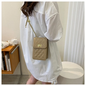 Detail of beige quilted mini bag featuring a gold chain and spherical adjustment buckle