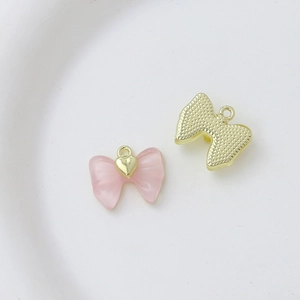 Detail view of pink frosted heart pendant with golden bow and metal ring for DIY jewelry