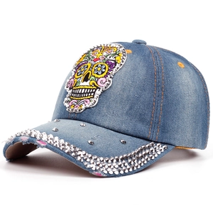 Detail of blue denim baseball cap with sugar skull embroidery and silver studs
