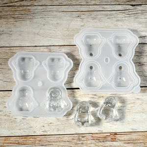 Detailed overhead view of 4-cavity penguin silicone ice cube molds on a wood background