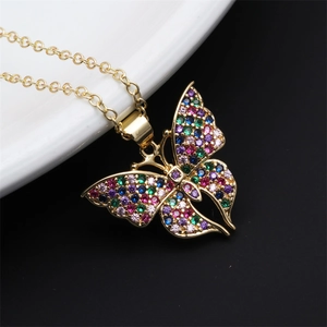 Detailed close-up of a golden butterfly pendant set with colorful rhinestones on black