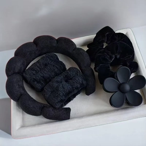 Detail view of 6-piece black spa headbands, wristbands, scrunchies and flower hair claw set
