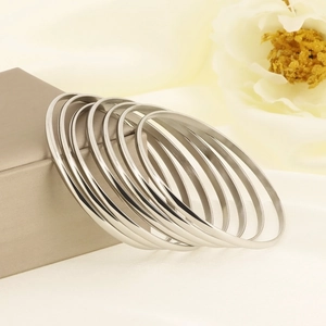 Polished silver 3.5mm 18k titanium steel bangle set of seven on elegant satin background