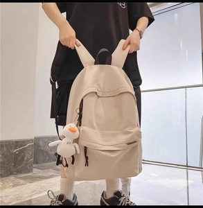 Dettaglio dello zaino in tela crema con design multitasche e ciondolo a forma di anatra
