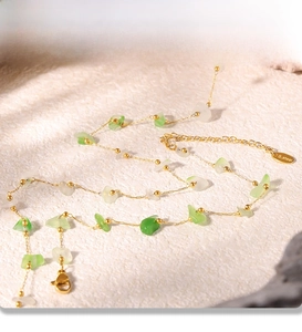 Detail of a PVD gold plated stainless steel necklace with green and white natural stones