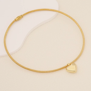 Detailed close-up of a polished gold heart pendant on a textured snake chain necklace