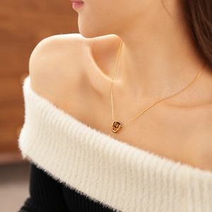 Close-up of golden U-shaped tiger eye stone pendant necklace worn by a female model