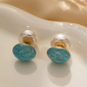 Detail of blue marble stud earring with oversized pearl back on white tray