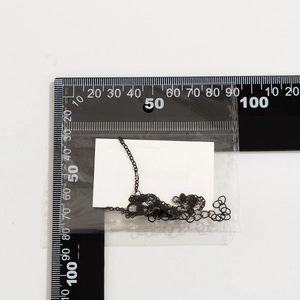Detail view of gothic black beaded choker with packaging scale for size reference