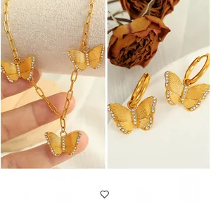 Detailed macro view of gold butterfly jewelry set with zircon stones and paperclip chain