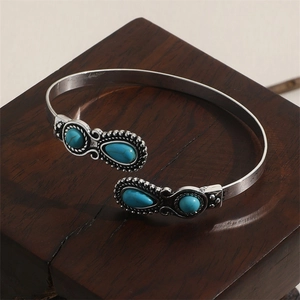 Macro detail of retro alloy bangle with turquoise stones on dark wooden base