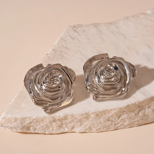 Vue macro de boucles d'oreilles rose en métal argenté sur pierre et fond chaleureux