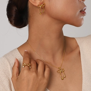 Golden bow jewelry set with necklace, earrings and ring on model with heart charms