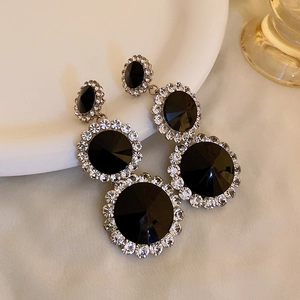 Close-up of black faceted stone earrings with triple-layered silver rhinestone borders