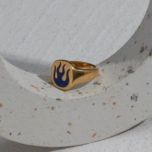 Detailed shot of gold plated signet ring with blue enamel fire pattern on a stone pedestal