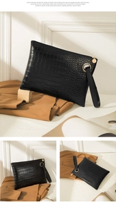 Detailed view of a black crocodile pattern clutch bag with golden hardware