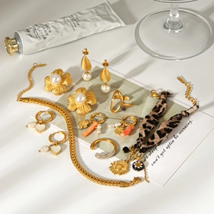 Detailaufnahme eines goldenen Schmucksets mit Perlenohrringen und flacher Schlangenkette
