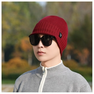 Detail of burgundy knit beanie with visor showing ribbed texture and brand tag