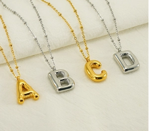Close-up of golden and silver balloon style alphabet pendants on beaded chains