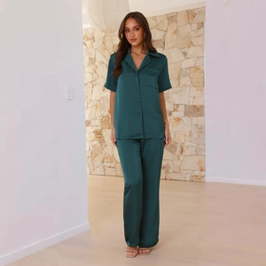 Detail of dark green satin pajama set with button-down shirt and matching trousers