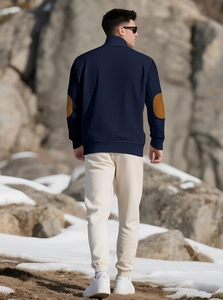 Detail of navy knit sweater featuring brown elbow patches and textured diamond pattern