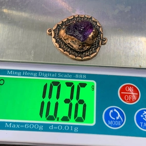 Macro-opname van een bronzen vintage connector met amethist edelsteen op een digitale weegschaal