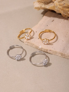 Detailed close-up of gold and silver flower rings with 5A zircon on natural stone