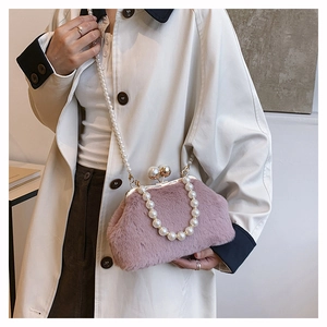 Detailed view of pink faux fur shell bag featuring pearl handles and gold orb clasp