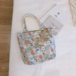 Flat lay of vintage floral cotton handbag with Animal Patterns label on white bedding