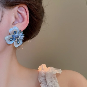 Detailed close-up of light blue 3D flower earring with resin petals and blue crystal center