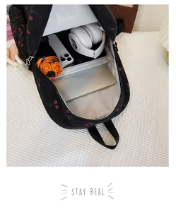 Interior storage space of black corduroy cherry backpack showing laptop and essentials