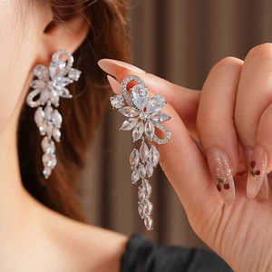 Detailed view of large sparkling zircon flower tassel earrings worn by a model