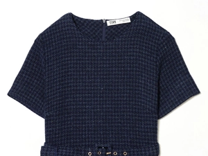 Détail d'une robe en tweed bleu marine avec texture gaufrée et ceinture à œillets métal