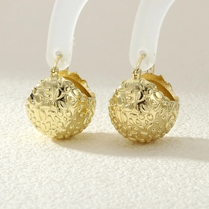 Detailed view of gold spherical earrings featuring a unique textured irregular finish