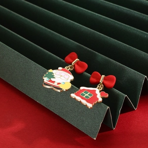 Detail of Christmas earrings featuring Santa Claus, a red house, and festive bows
