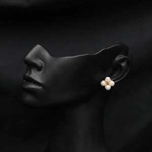 Detail of flower shaped freshwater pearl stud earrings on a black model silhouette