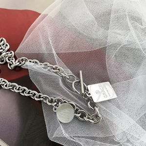 Detalle de collar de cadena con cierre OT en acero inoxidable con colgantes grabados