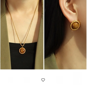Macro detail of luxury tiger eye necklace and earrings set with twisted gold textures