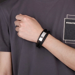 Detail of men's triple-layer braided leather bracelet with silver steel curved plaque